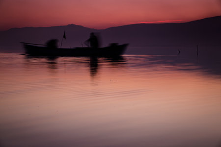 A beautiful shot of the sea with the silhouette of a boat at sunsetの写真素材