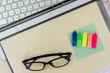 A top view of a workplace composition with a laptop, folder, glasses, and supplies offices on desk