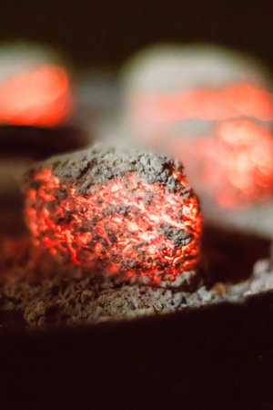 A closeup shot of a red glowing coal on an iron cover of a dutch oven.の写真素材