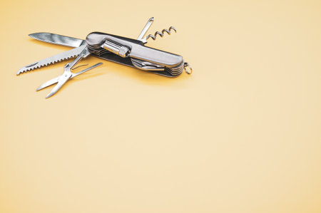A high angle shot of a swiss army knife on a yellow surfaceの写真素材
