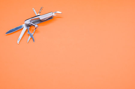 A high angle shot of a swiss army knife on an orange surface