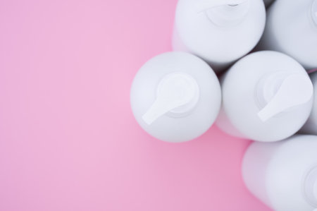A high angle shot of white plastic bottles on a pink surfaceの写真素材