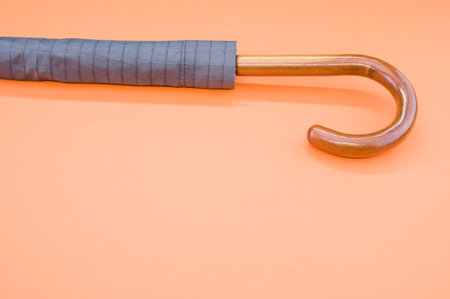 A high angle shot of an umbrella with a wooden handle on an orange surfaceの写真素材