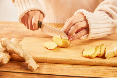 A female cutting a ginger on a chopping boardの写真素材
