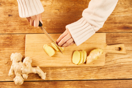 A female cutting a ginger on a chopping boardの写真素材