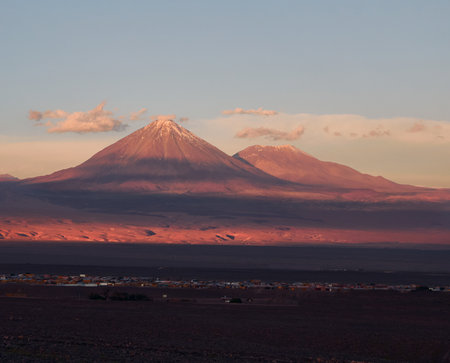 A mesmerizing view of the high mountains with the tops covered in snow gleaming under the sunsetの写真素材