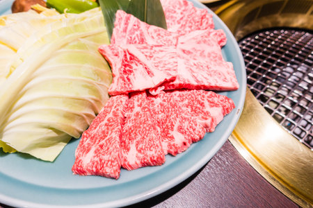 A closeup of premium Kobe beef steak and fresh vegetables on a light blue plateの写真素材