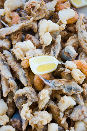 A portion of mixed fried seafood with a slice of fresh lemonの写真素材