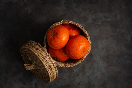 A top view of tangerines in a small basket, on a dark surfaceの写真素材