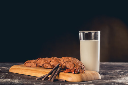 A closeup shot of chocolate and walnut cookies with a glass of milk on the sideの写真素材