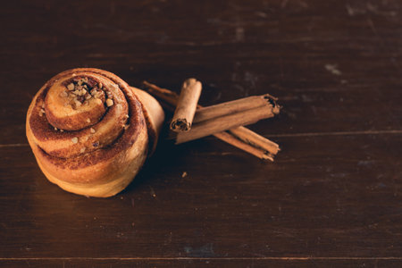 A closeup shot of a fresh cinnamon roll and cinnamon sticksの写真素材