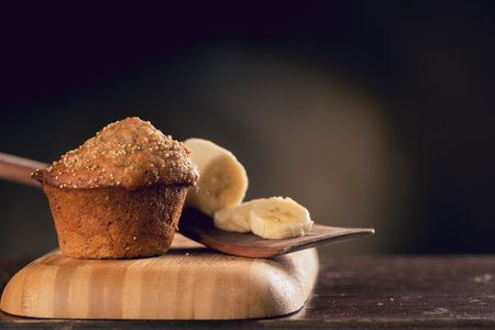 A closeup shot of a fresh muffin with bananas on a boardの写真素材