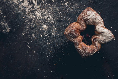 An overhead shot of an iced raspberry flower bread on a black tableの写真素材