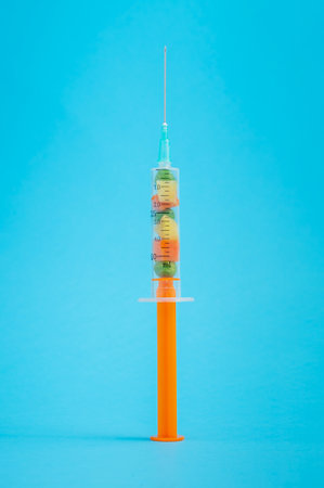 A vertical shot of a syringe full of tiny vegetables on blue backgroundの写真素材