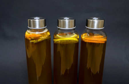 A closeup of three bottles of tea with lemon slices against a gray backgroundの写真素材