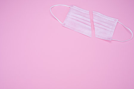 A high angle shot of a facemask cut in half on a pink surface - COVID-19の写真素材