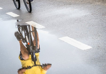 The reflection of a cyclist in the puddle of rainwaterの写真素材