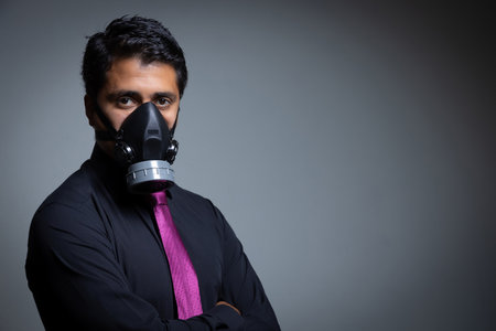 A closeup shot of a businessman protecting himself with a mask from the pandemicの写真素材