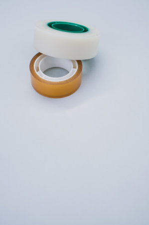 A vertical shot of two rolls of sticky tapes isolated on a gray backgroundの写真素材