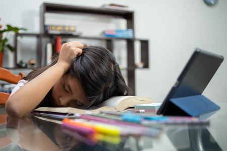 A pretty little Hispanic girl sleeping on her books and feeling tired of studying - online educationの写真素材