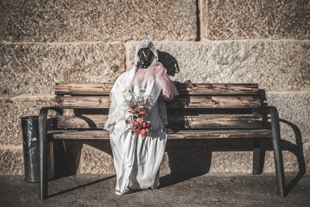 A mannequin dressed as a ghost bride for Halloween sitting on a wooden bench outdoorsの写真素材