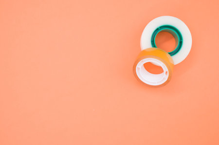 A top view of two rolls of sticky tapes isolated on an orange backgroundの写真素材
