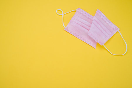 A high angle shot of a facemask cut in half isolated on a yellow background - COVID-19の写真素材