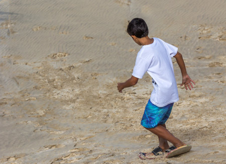 A closeup shot of a boy going down the dunesの写真素材