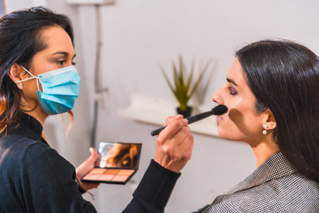 A makeup artist with a protective mask working in a beauty salon. Security measures of aesthetic centers in the Covid-19 pandemicの写真素材