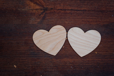 Two white wooden hearts lie on a brown wooden surface, valentine's dayの写真素材