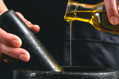 A cook pouring olive oil into the mortarの写真素材