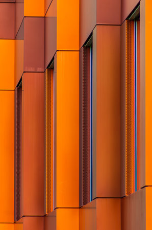 A vertical shot of a modern building with red and orange colors