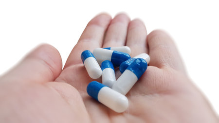 A hand holding capsules on white background