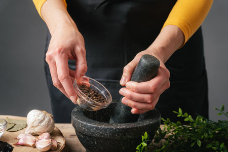 Woman hands pouring peppercorns into a mortar for grindingの写真素材