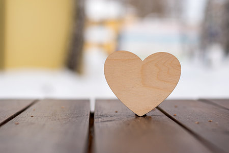 One wooden heart stands on a brown table on a light abstract background, valentine's dayの写真素材
