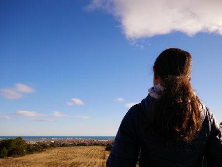 A back view of a female looking at the view of a fieldの写真素材