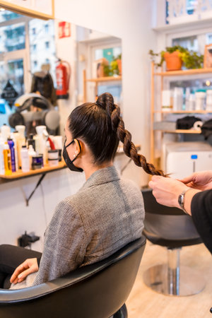 A hairdresser giving the final touches to the client's hairstyle. Security measures of hairdressers...