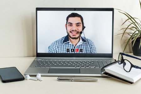 A male working in a call center on a video call on the laptop