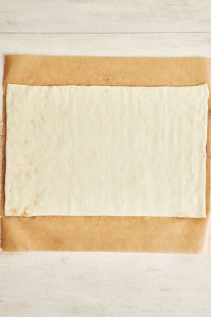 A top view of raw dough for cinnamon rolls on a parchment paper on the tableの写真素材