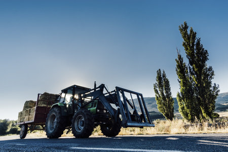 A tractor loaded with bay hales driving on a road at daytimeの写真素材
