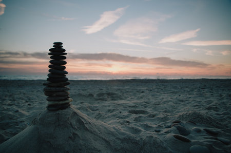 A selective focus shot of zen stones at the sandy beach during sunsetの写真素材