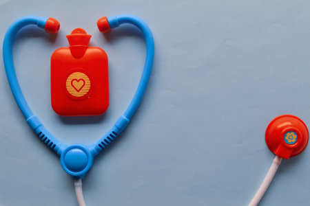 A top view of a blue toy stethoscope next to a hot water bag