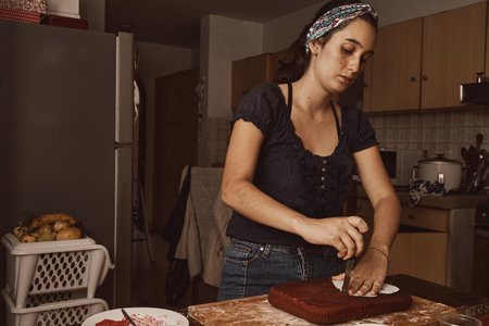 A Hispanic woman making a heart-shaped cake in a kitchenの写真素材
