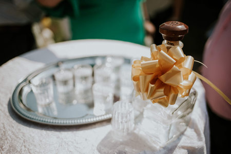A closeup of a decorated bottle for drinks with shot glasses on a tray on the tableの写真素材