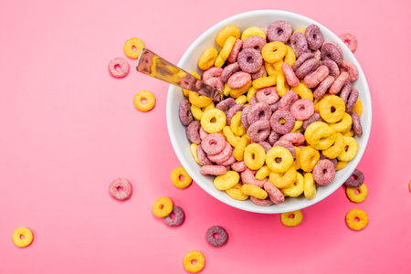 A top view of a bowl of cereal with a spoon on a pink surface under the lightsの写真素材