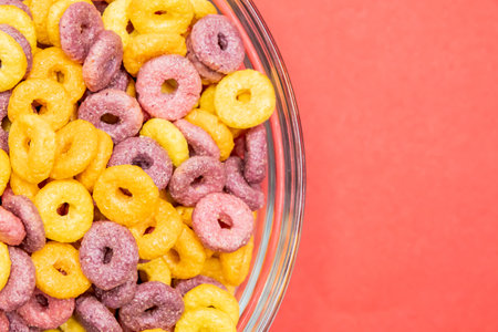 A top view of colorful cereal rings on a bowl isolated on red background