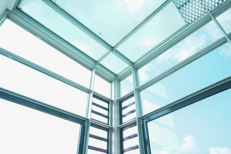 A low angle shot of the sky visible through the glass walls and ceiling of a modern building
