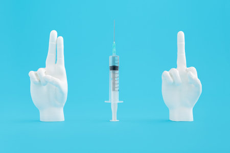 A syringe with a mannequin finger showing signs on a blue backgroundの写真素材