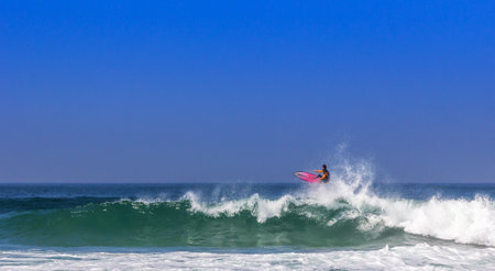 A surfer surfing on sea waves under a bright skyの写真素材