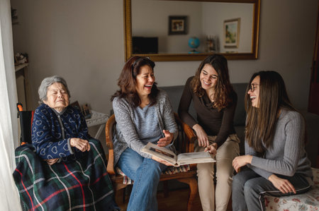 A sick grandmother sitting in wheelchair next to daughter and granddaughters looking a photo album